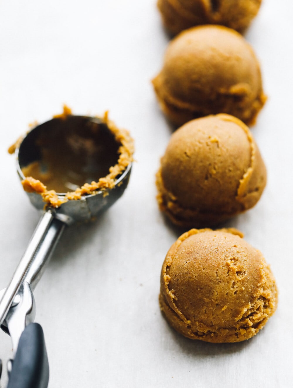 ginger molasses cookie dough in balls with a cookie scoop next to them