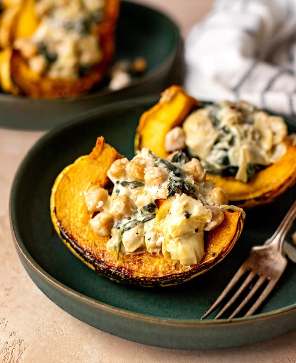 roasted carnival squash stuffed with spinach artichoke dip, on a green plate