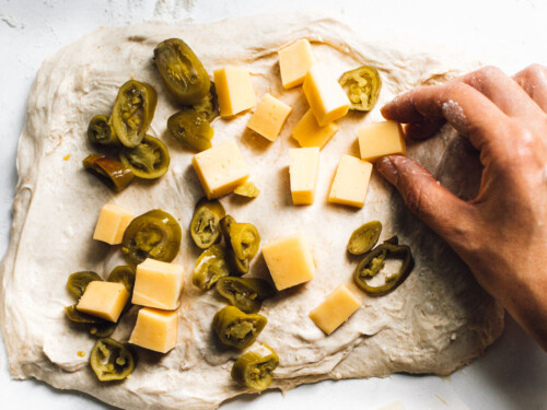 adding cheese and jalapenos to bread dough