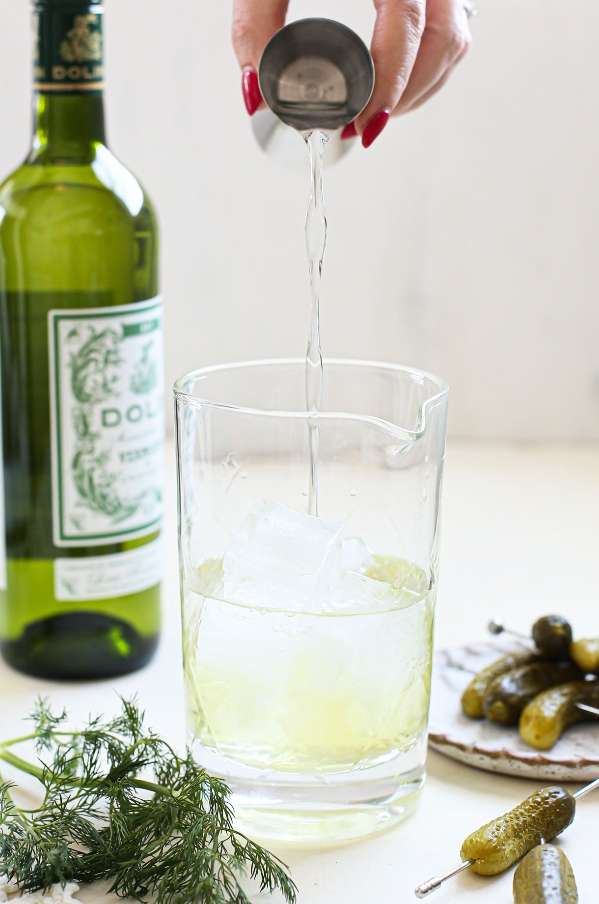 mixing a dill pickle martini in a glass