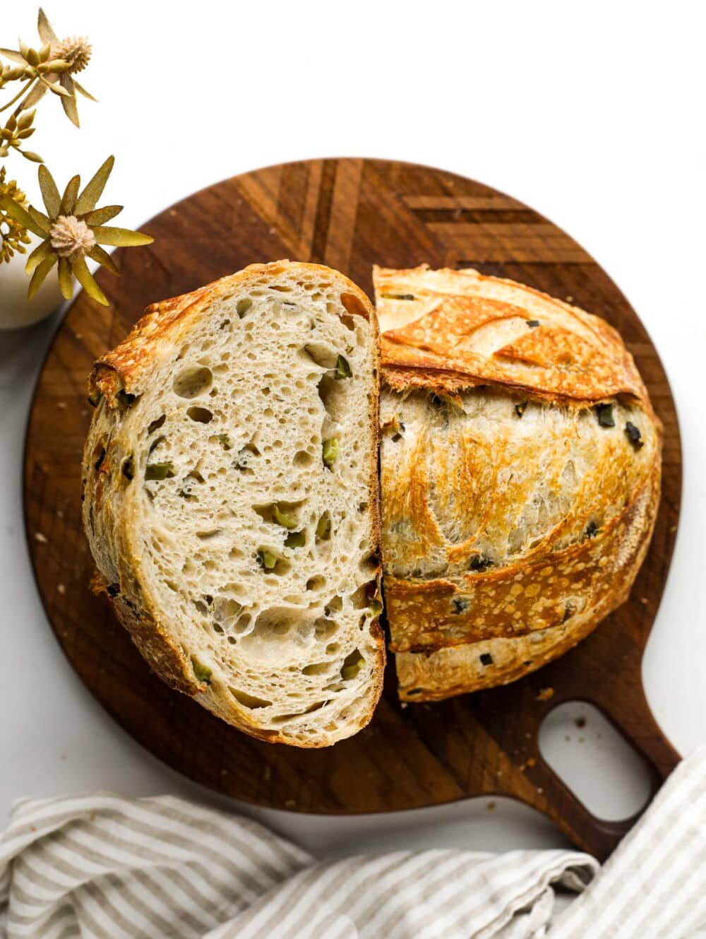 sourdough bread cut in half with crumb showing, on a wooden cutting board