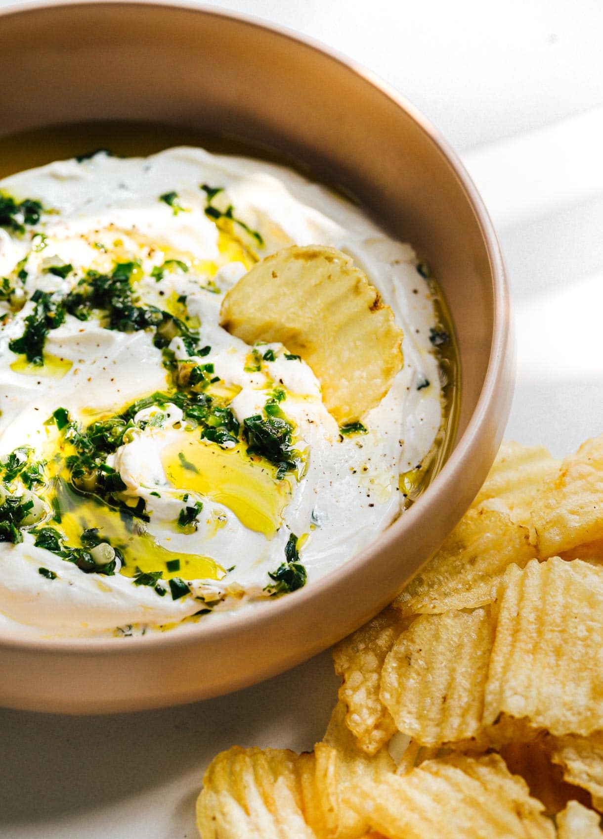 sour cream and ramp dip in a pink bowl with potato chips on the side