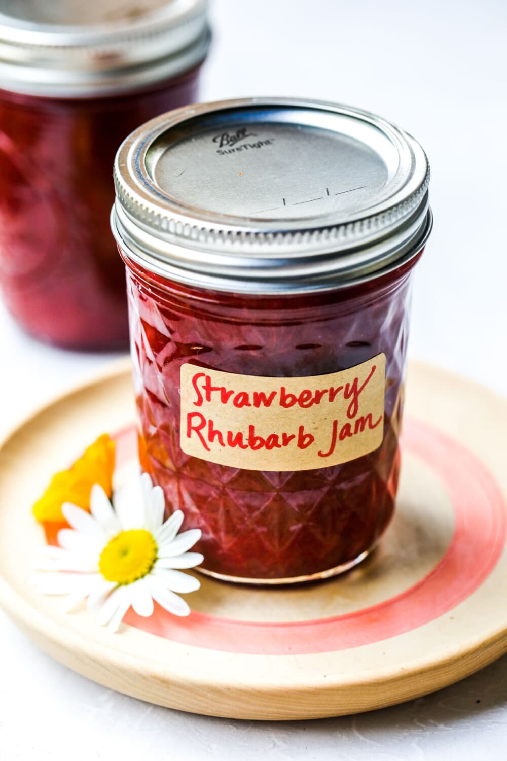 strawberry rhubarb jam in glass jars on wooden coaster
