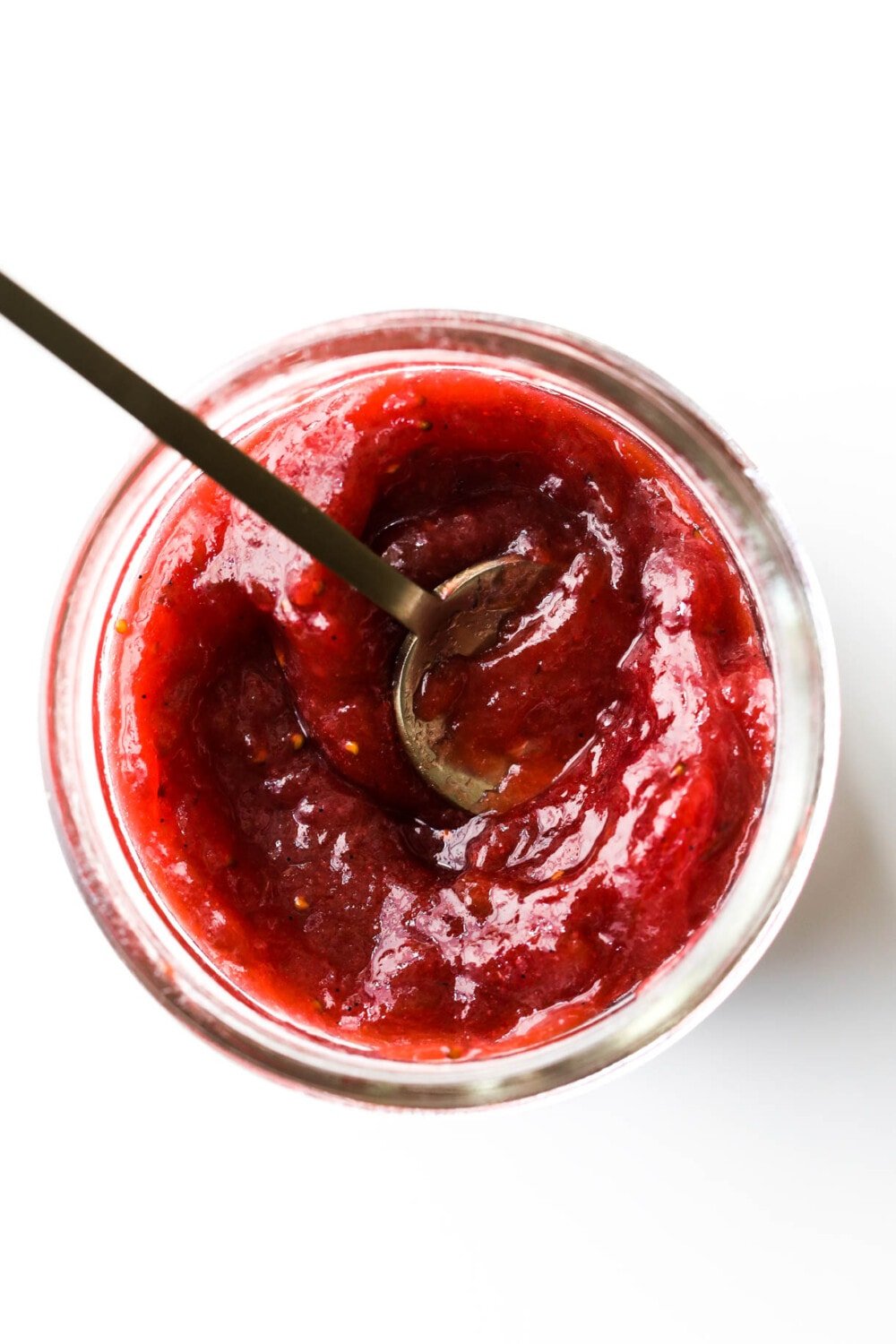 strawberry rhubarb jam in a clear jar with spoon
