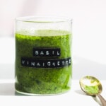 basil vinaigrette in a glass jar with gold spoon next to it