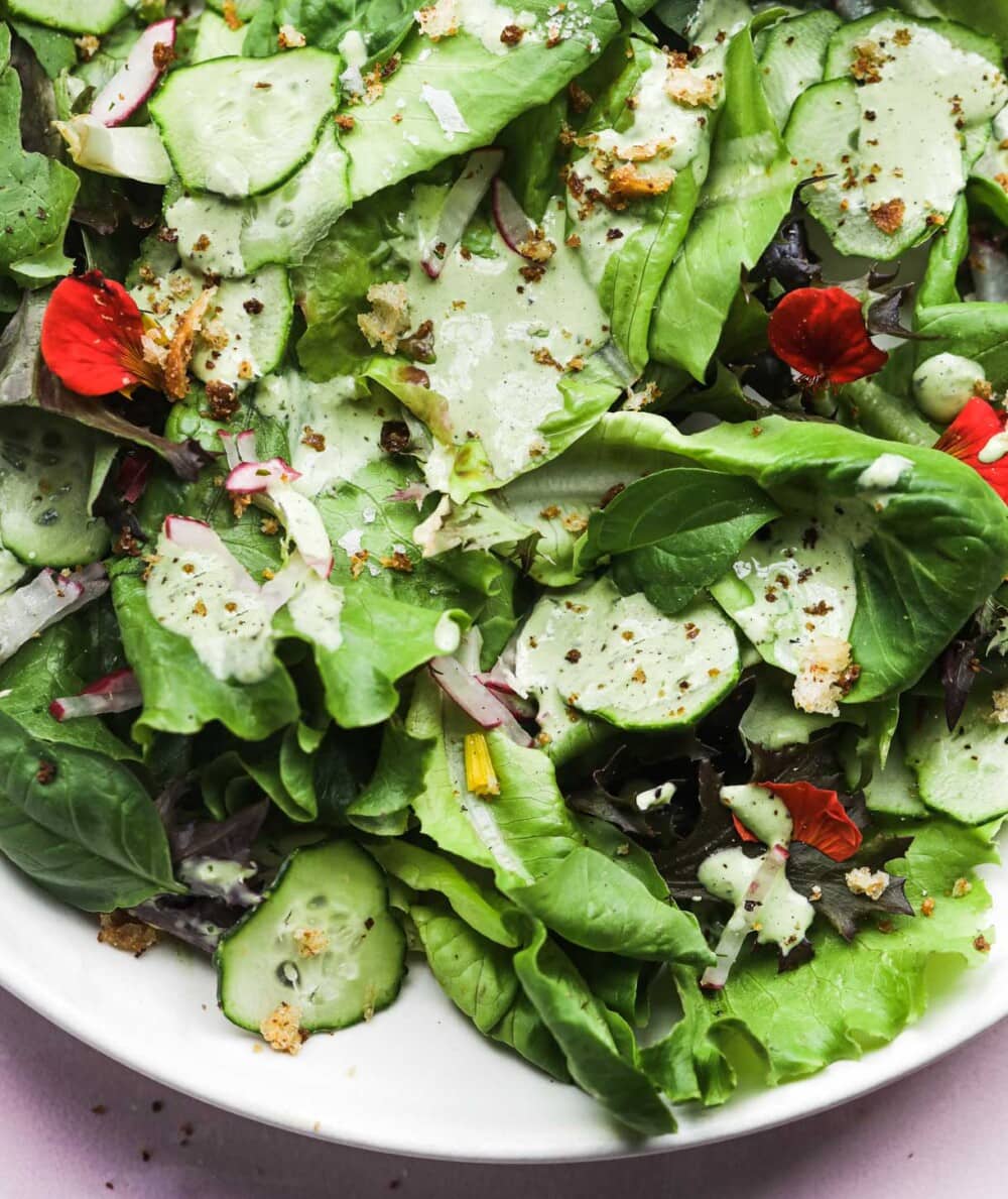 fresh greens with green goddess salad dressing, on white plate