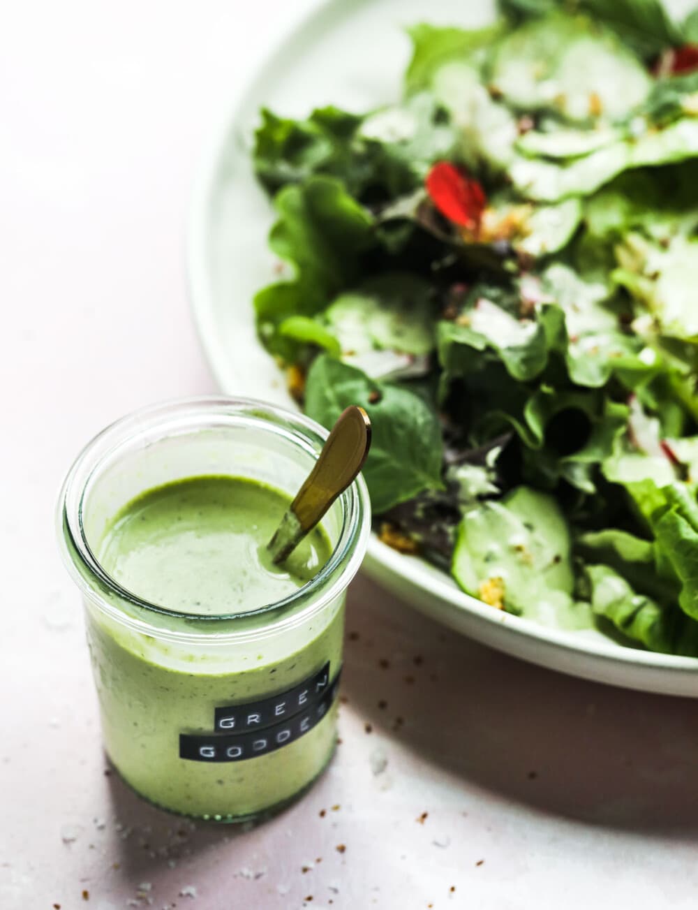 green goddess salad dressing in a glass jar and on a salad