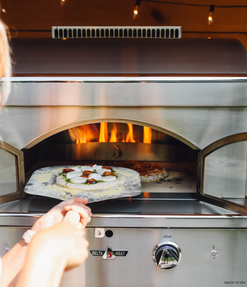 putting pizza into a delta heat pizza oven with pizza peel