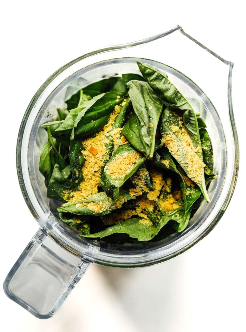basil leaves and nutritional yeast in a blender jar