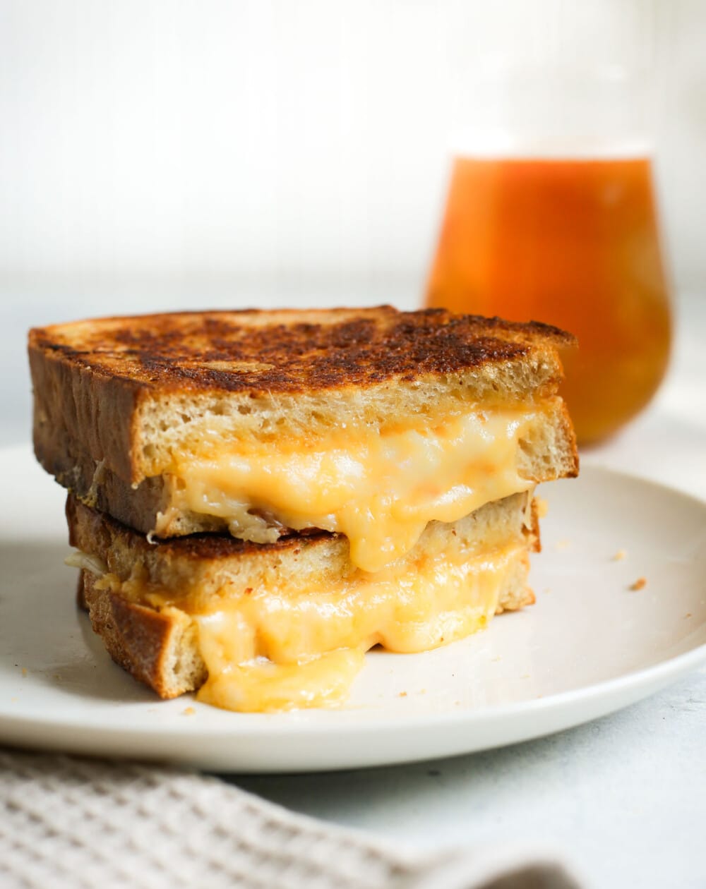 sourdough grilled cheese cut in half and stacked on top of each other on white plate