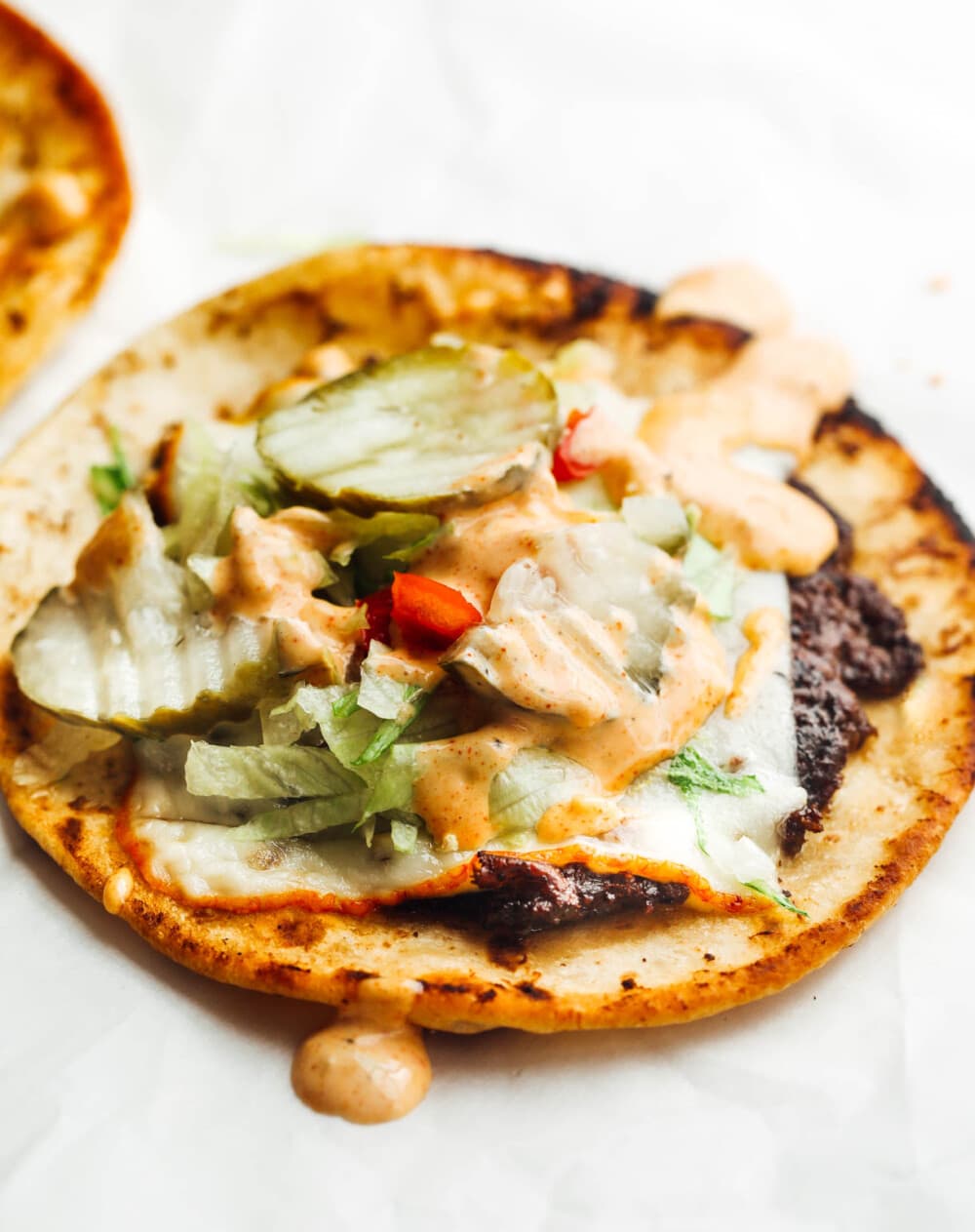 viral smash burger tacos with fixings on parchment paper