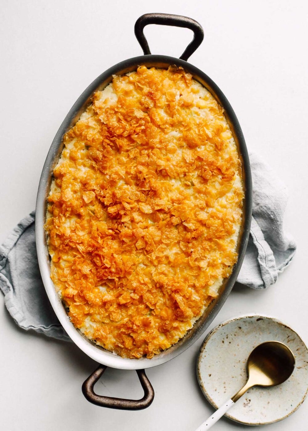 creamy baked corn in a casserole dish with gold spoon on the right side