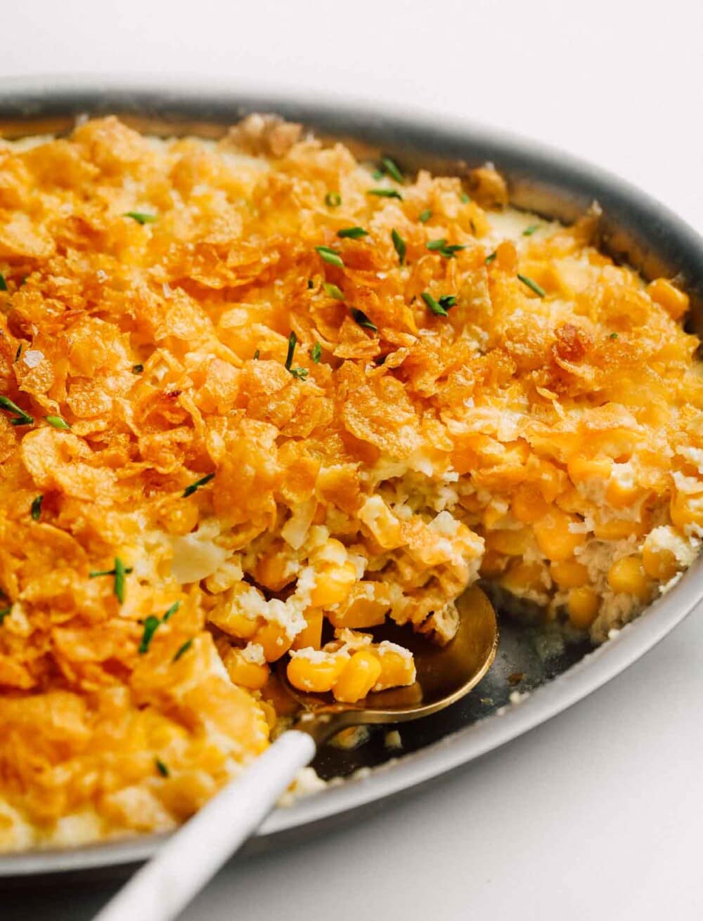 baked corn casserole in pan with gold spoon