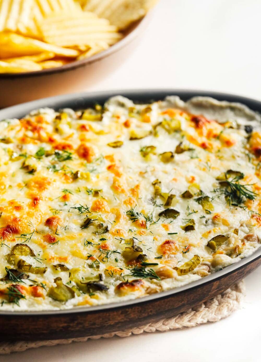 baked dill pickle dip in a casserole dish that is sitting on a hot pad