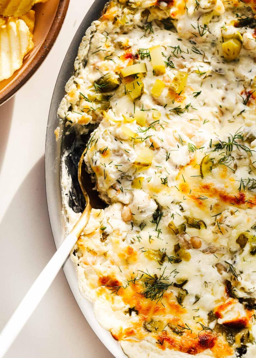 baked pickle dip in a casserole dish with gold spoon