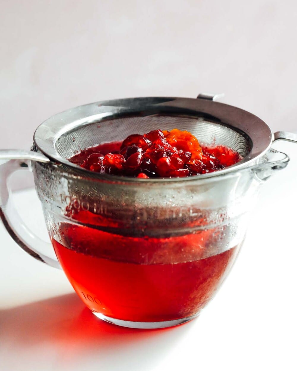 fresh cranberry syrup straining over glass bowl