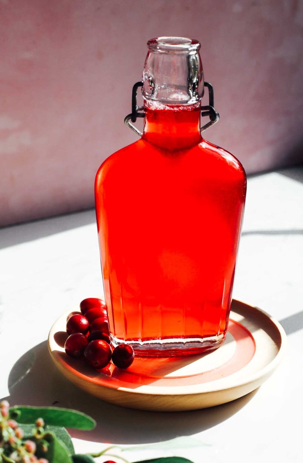 cranberry syrup in clear bottle with berries to the left of the bottle