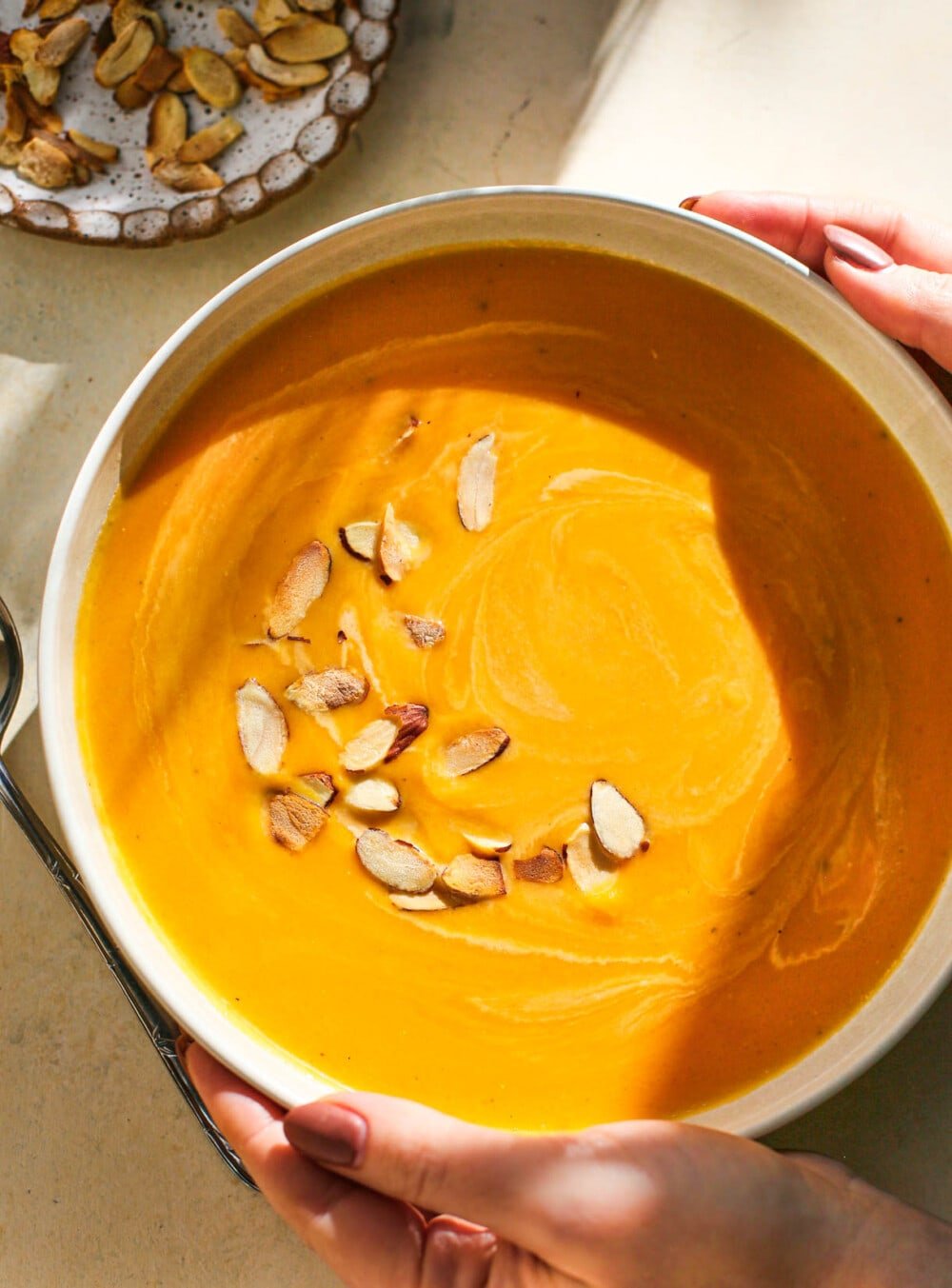 woman holding bowl of butternut squash bisque in white bowl