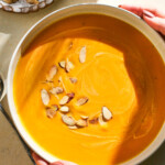 woman holding bowl of butternut squash bisque in white bowl