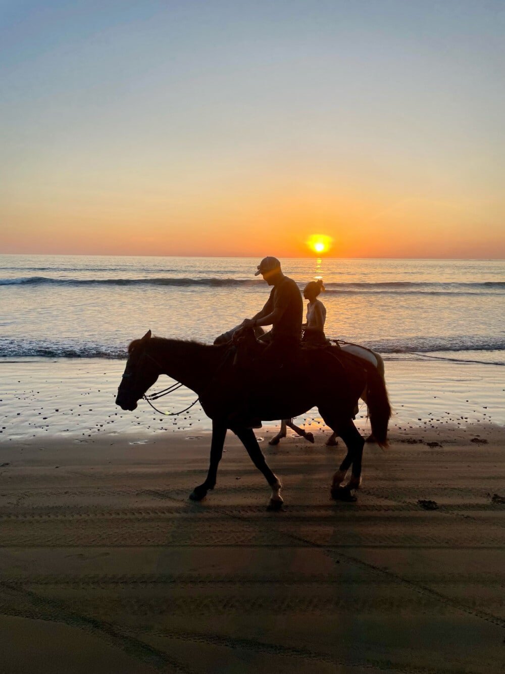 horse back riding on a beach in costa rica at sunset