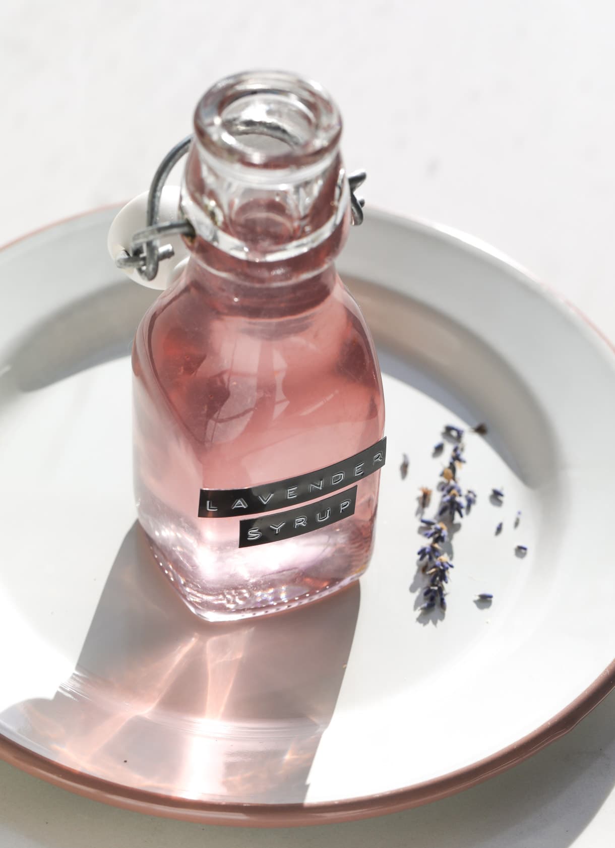 lavender simple syrup in clear bottle on white plate