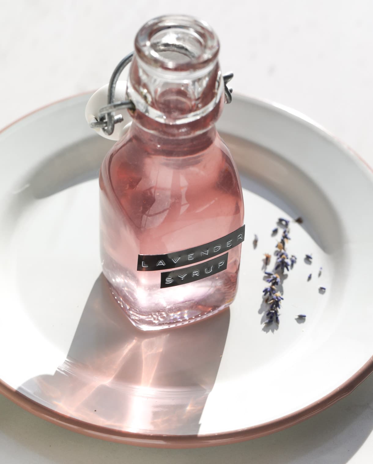 lavender simple syrup in small bottle on a white plate