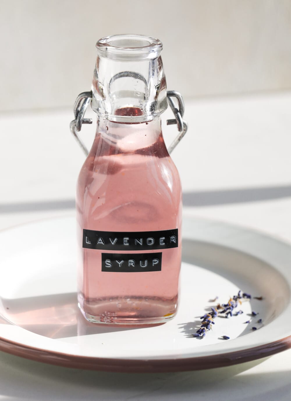 lavender syrup in a glass bottle on a white plate