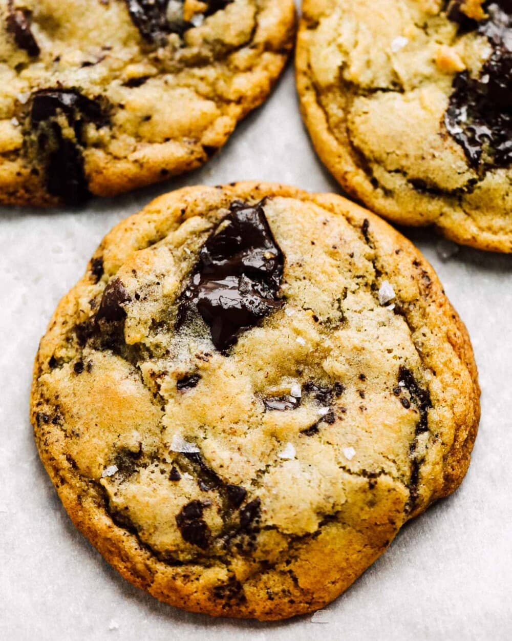 gooey sourdough chocolate chip cookies on white parchment paper