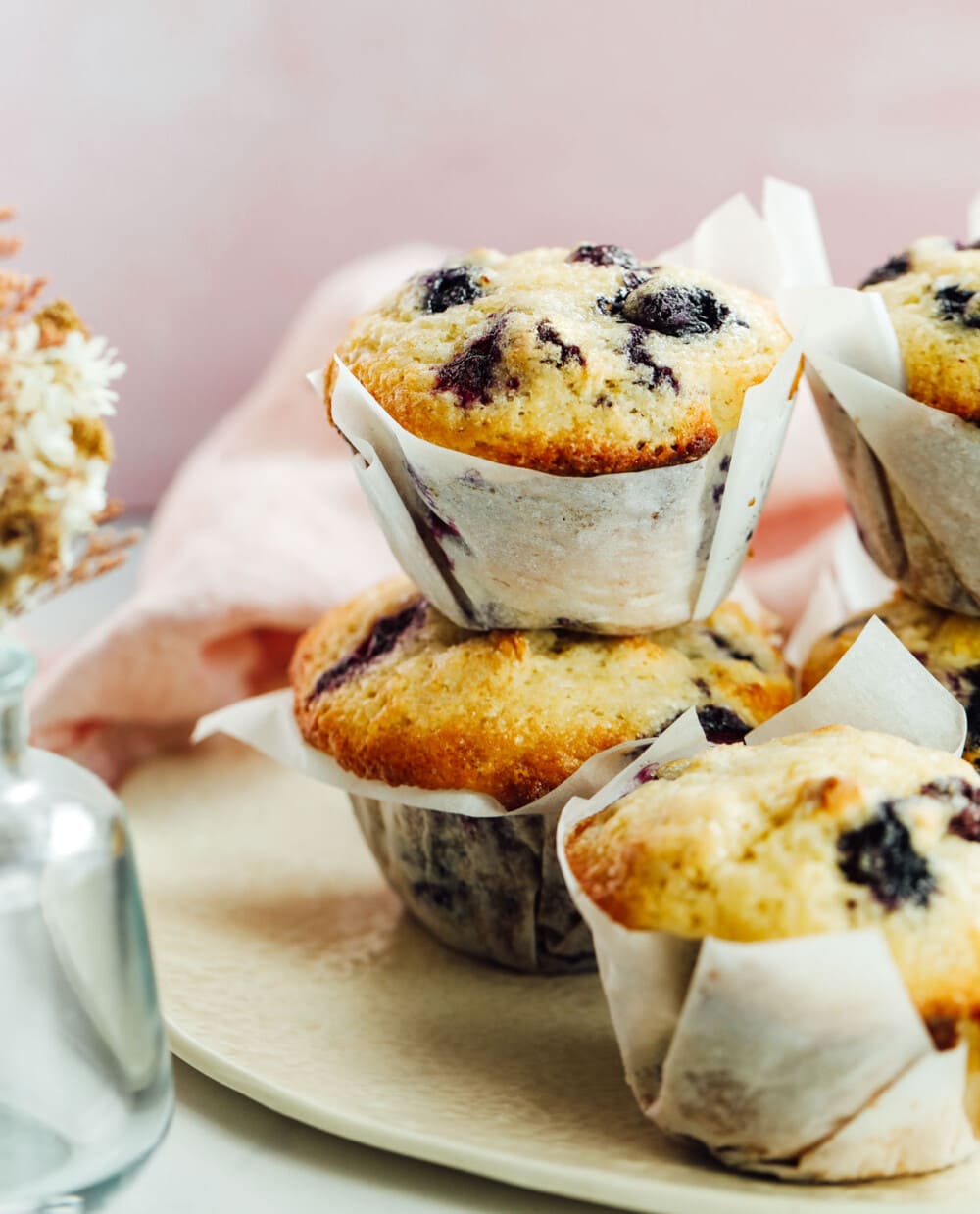 sourdough blueberry muffins stacked with pink linen behind them