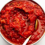 stewed tomatoes in bowl with gold spoon