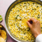 Corn dip with tortilla chips and hand dipping with a chip