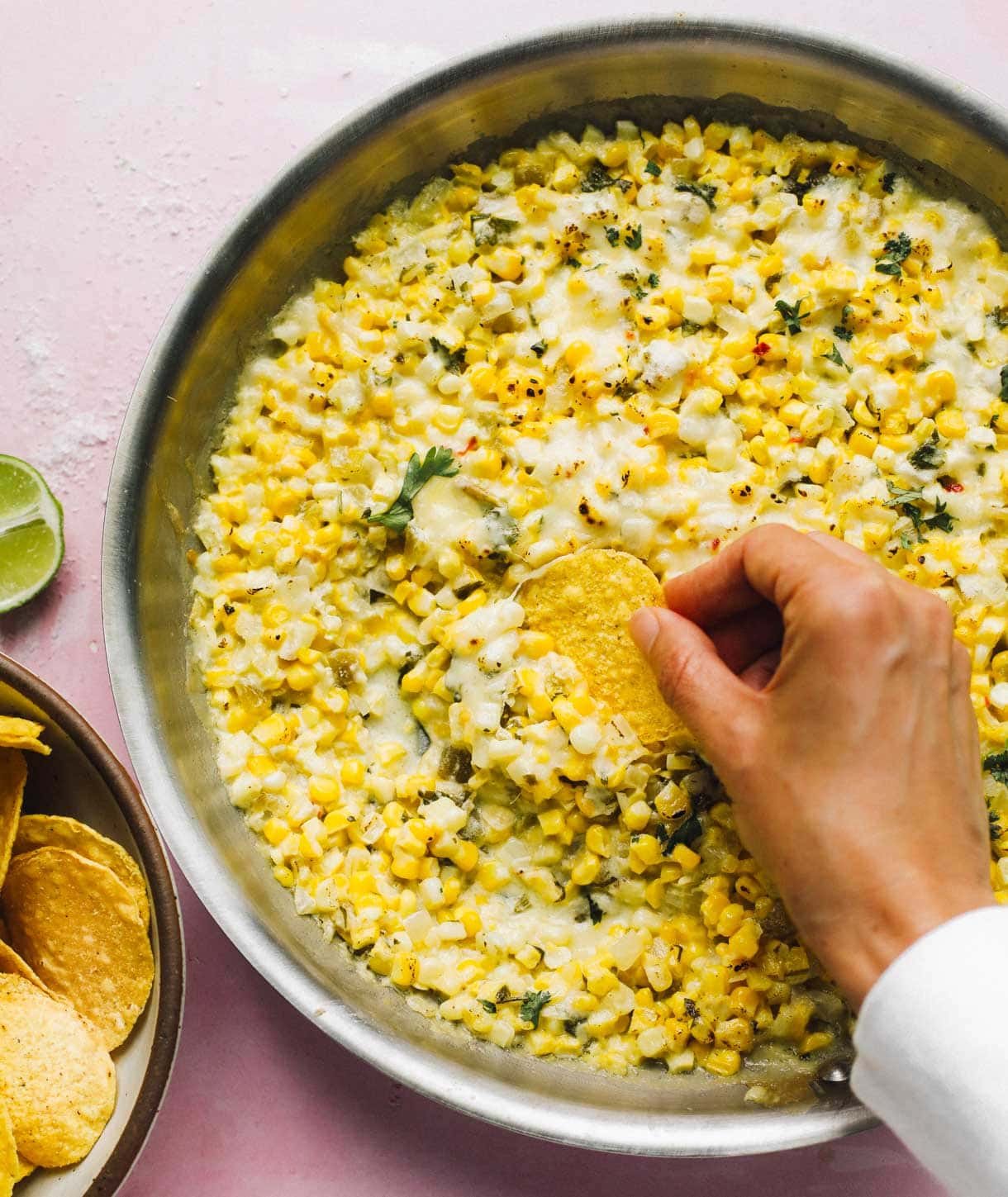 Corn dip with tortilla chips and hand dipping with a chip
