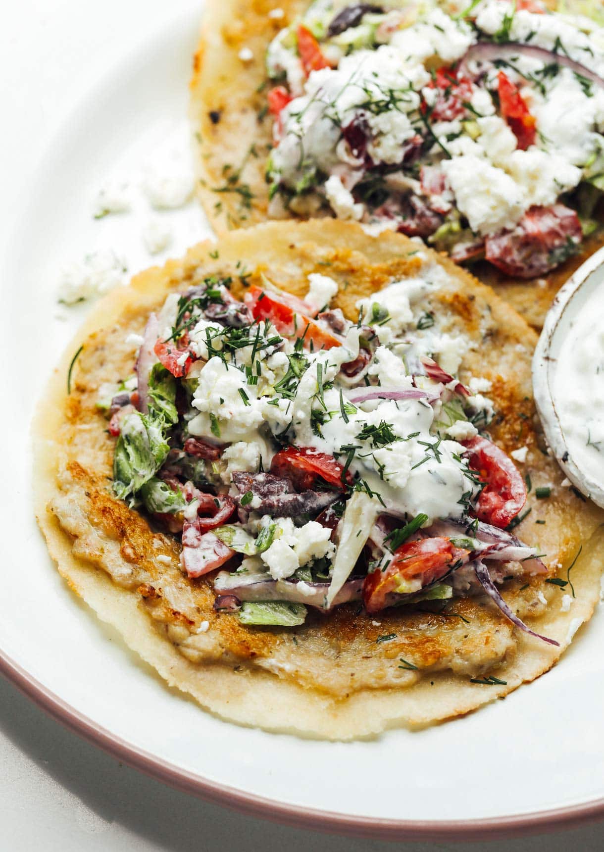 Two greek ground chicken smash tacos on a plate.