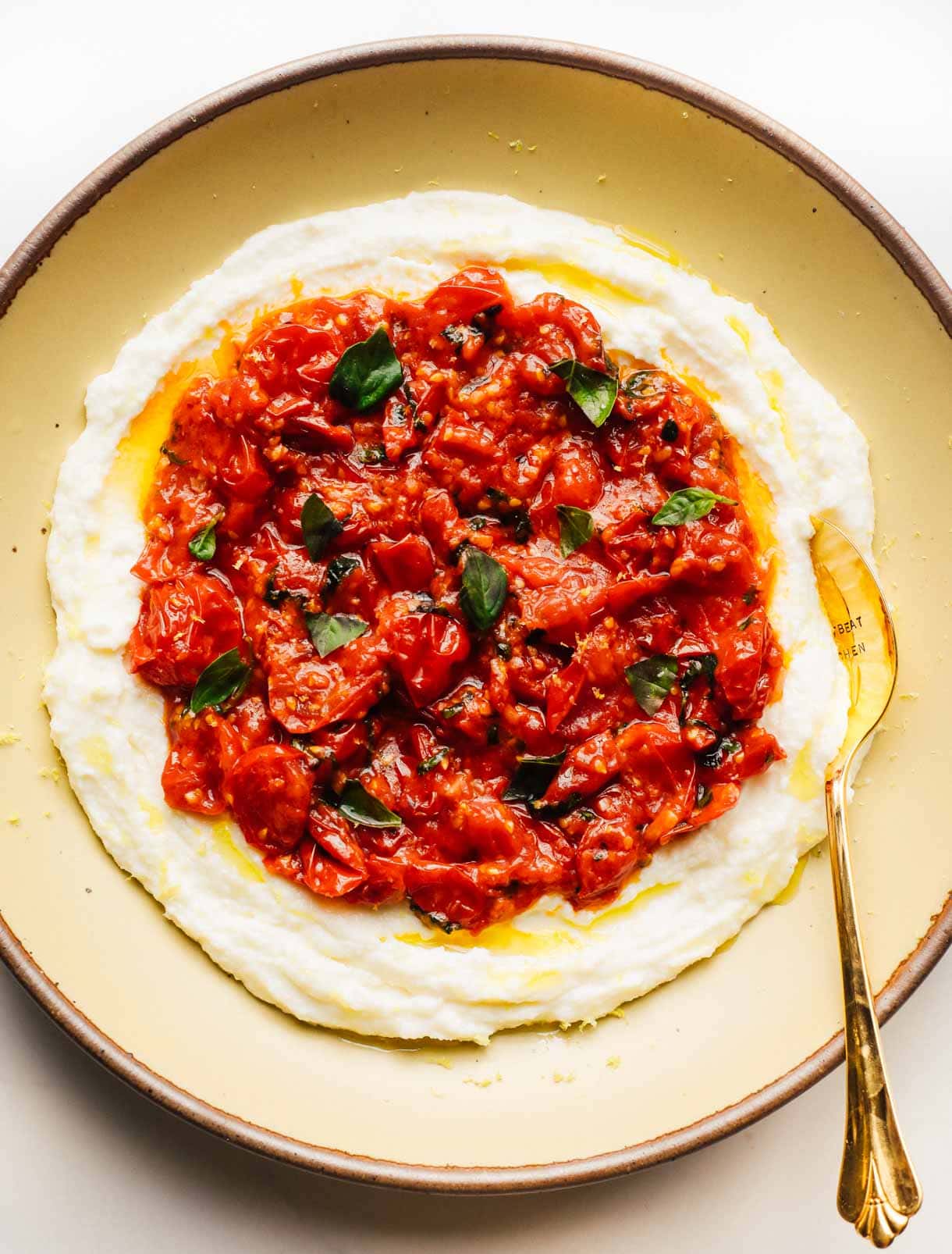whipped mozzarella with tomatoes on top on a yellow plate