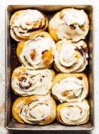 a pan of sourdough cinnamon rolls slathered with cream cheese frosting