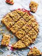 gluten-free rhubarb crumble bars cut into squares, on parchment paper