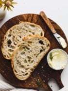sliced dill pickle sourdough bread on cutting board with small bowl of butter and knife