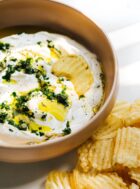 sour cream and ramp dip in a pink bowl with potato chips on the side