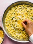Corn dip with tortilla chips and hand dipping with a chip
